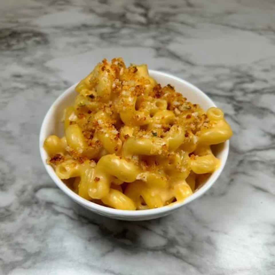 A white bowl of creamy Deja Soul mac and cheese with a crispy breadcrumb topping.